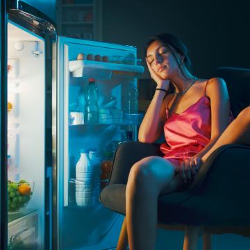Risolatte Senza Zuccheri Aggiunti: La Ricetta Facile e Salutare per un Dessert Gustoso e Dietetico - Ragazza che dorme davanti al frigorifero aperto, aspettando che il risolatte senza zuccheri aggiunti si raffreddi.